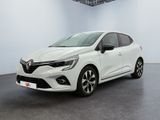 Une voiture blanche est garée dans une pièce au sol noir.