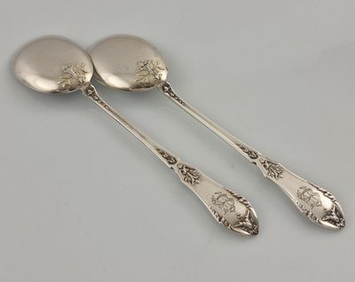 deux cuillères en argent et une cuillère posées sur une surface blanche