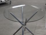 une table en verre avec un piètement en métal au milieu d'une pièce