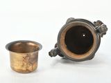a small metal cup next to a smaller metal cup