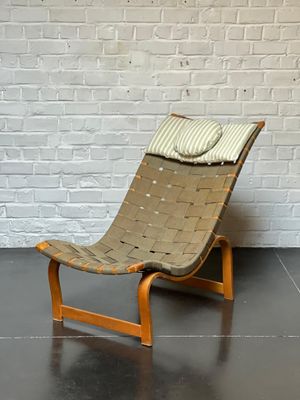 une chaise sur laquelle est posé un coussin, devant un mur de briques blanches