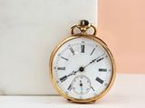 a gold pocket watch sitting on a marble block