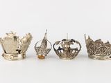 four silver crowns are lined up in a row on a white surface
