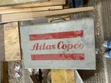 a sign that says atlas coffee on it in front of a pile of wood