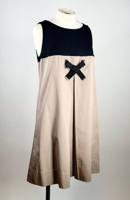 robe beige et noire ornée d'un nœud, posée sur un socle de mannequin