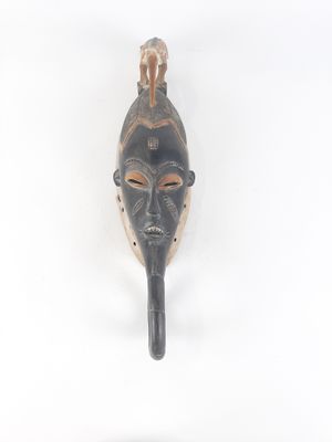 an african mask hanging on a wall with a white background