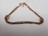 un collier doré et rose sur fond blanc