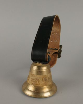 clochette en laiton avec un cordon en cuir noir sur fond gris