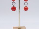 pair of red coral and diamond earrings on a wooden stand