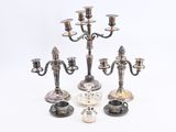trois chandeliers en argent sont posés sur une surface blanche