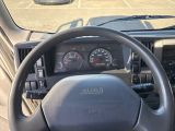 a steering wheel and dashboard of a truck in a parking lot