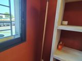 une étagère avec un balai à côté d'une fenêtre dans une pièce