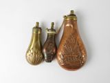 three antique brass vases are sitting next to each other on a white surface