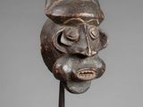 a close up of a wooden mask on a metal stand