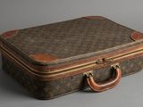 une valise marron et beige posée sur une surface grise