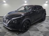 the black nissan juke suv is parked in a showroom