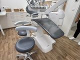 a woman standing next to a chair in a dentist ' s office