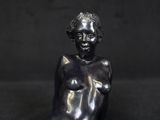 statue of a woman sitting on a black surface