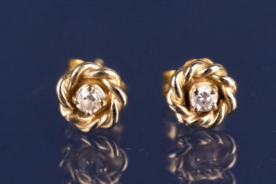 une paire de boucles d'oreilles en or jaune et diamants sur un fond bleu