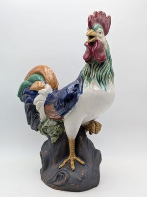 une figurine représentant un coq debout sur un rocher