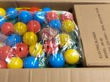 a cardboard box filled with plastic balls and a bunch of candy