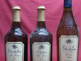 three bottles of wine are lined up against a pink backdrop