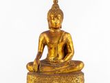 une image représentant une statue de Bouddha en or posée sur un bloc de bois