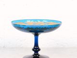 une image représentant un bol en verre bleu posé sur une table