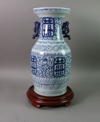 un vase bleu et blanc posé sur un socle en bois