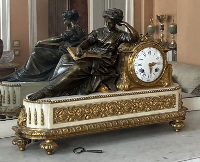 a statue of a woman sitting on a bench with a clock