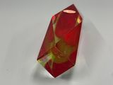 a close up of a red and yellow crystal on a white surface