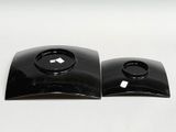 pair of black plastic speakers on a white surface with a white background