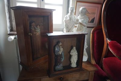 trois statues de Jésus et de Marie posées sur une table à côté d'une chaise rouge