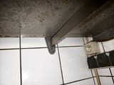 a picture of a dirty bathroom floor with a rusted door handle