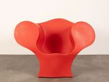 an orange chair sitting on top of a cement floor next to a white wall
