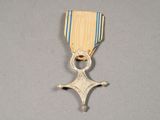 une vieille médaille ornée d'une croix, posée sur un fond gris
