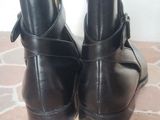 pair of black leather ankle boots with buckles on a tiled floor