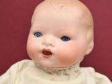 a small doll with blue eyes sitting on a red surface
