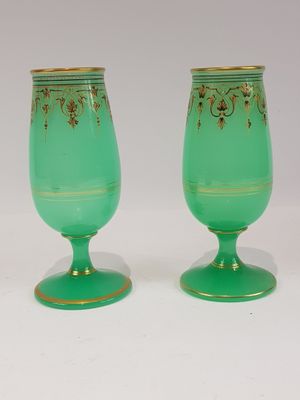 une paire de verres à pied en verre vert ornés de motifs dorés