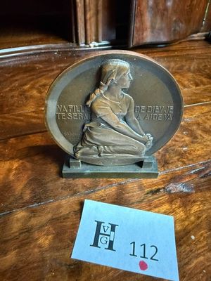 a silver medal on a wooden table with a sticker next to it