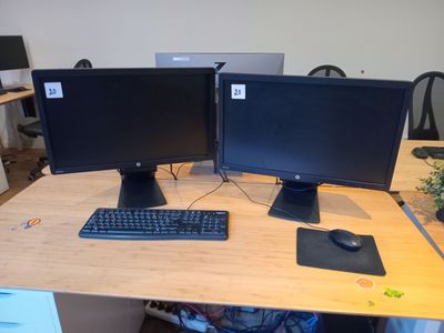 deux écrans d'ordinateur posés sur un bureau avec un clavier et une souris