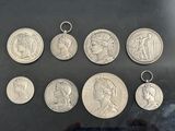 six silver coins of different sizes and shapes on a black surface