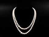 un collier de perles blanches composé de deux rangs de perles, posé sur un mannequin noir