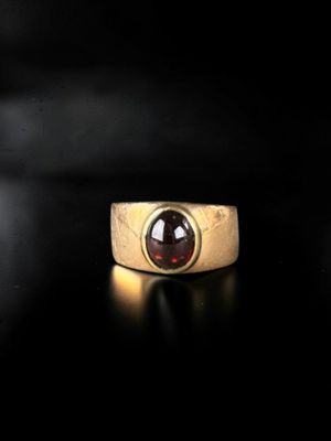 a close up of a gold ring with a red stone in it
