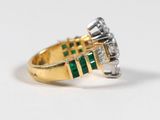 a close up of a diamond and emerald ring on a white surface