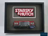 une photo encadrée représentant une voiture rouge sur laquelle figurent les mots « Starsky et Hutch »