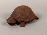 an old turtle figurine sitting on top of a white surface