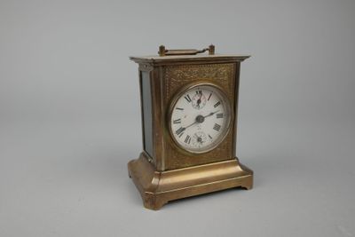 une petite horloge en laiton avec des chiffres romains sur le cadran
