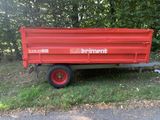 une photo d'un camion-benne rouge garé dans l'herbe