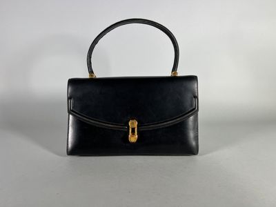 a black leather handbag with a gold handle on a white background